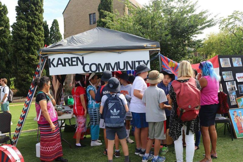 Children gathered at a Karen Community stall on a lawn at a multicultural race day in Victoria.