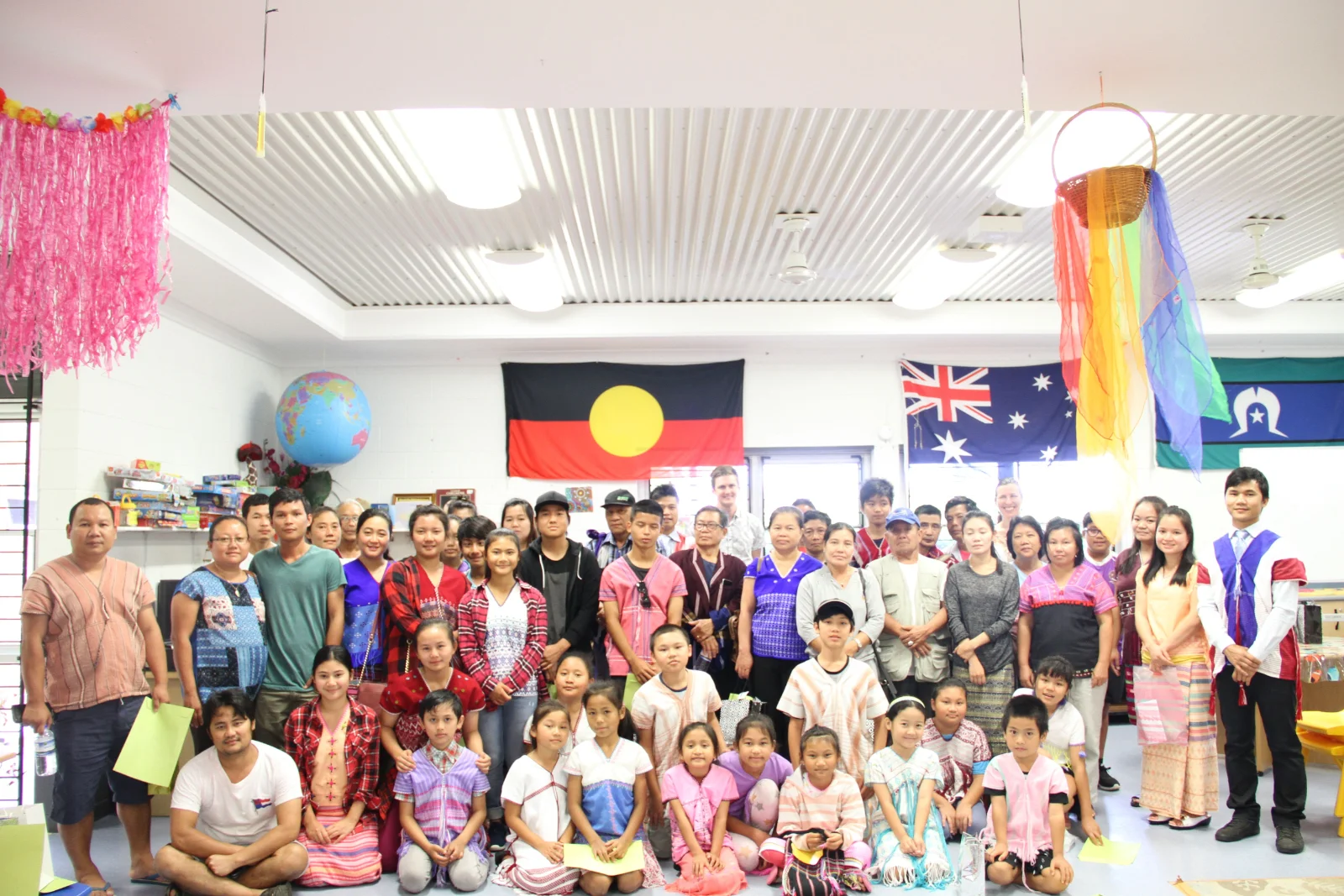 Students and teachers of the Karen language school gathered in a classroom under the Aboriginal, Australian and Torres Strait Islander flags.